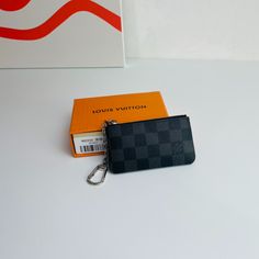 This Damier canvas pouch holds loose change and keys and slips easily into a handbag or coat pocket. 

Size: 12×7cm Gray Travel Bags With Card Slots, Black Pouch With Coin Pocket For Daily Use, Luxury Black Coin Purse With Interior Key Chain Holder, Gray Bags With Card Slots For Daily Use, Black Pouch With Card Slots For Personal Use, Gray Bags With Card Slots For Everyday Use, Modern Black Pouch With Card Slots, Black Wallets With Key Clip For Daily Use, Everyday Black Bag With Key Clip