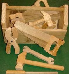 a wooden tool box filled with tools like hammers, nails and pliers on top of a green surface