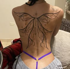 the back of a woman's body with tattoos on her upper and lower back