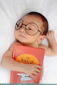 a baby wearing glasses and reading a book