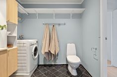 a washer and dryer in a bathroom with blue walls, tile flooring and wooden cabinets