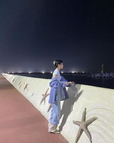 a woman standing on the side of a wall next to a starfish and ocean