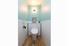 a bathroom with a white toilet sitting next to a wall mounted light above the toilet