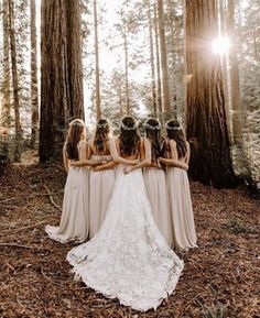 a group of bridesmaids standing in the woods with their backs to each other