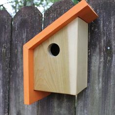 a bird house hanging on the side of a wooden fence