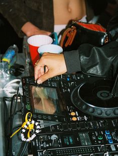 a dj mixing music on top of a table with cups and other items around it