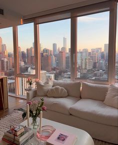 a living room filled with furniture and large windows overlooking the cityscape in the distance