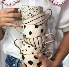 a woman is holding several coffee cups in her hands and wearing polka dots on them