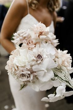 a bride holding a bouquet of white and pink flowers on her wedding day in front of the camera