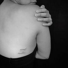 a woman with a tattoo on her back holding her hand to her shoulder and looking off into the distance