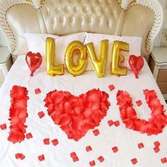 the bed is decorated with red and gold foil balloons that spell out i love you