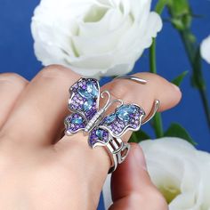 Our gorgeous flying butterfly ring, with its distinctive workmanship, pays tribute to the glamour and elegance of this creature. Through its graceful movement between your fingers, it recreates the fluttering charm of wings and adds unique enchantment to your femininity. Combing beautiful colors and asymmetry, this dazzling piece highlights eight brilliant marquise-cut blue stones, and smaller round stones in purple paved on wings. The multi-colored butterfly, fashioned in fine sterling silver, Fine Jewelry Butterfly Piece For Wedding, Fine Jewelry Butterfly Shape For Wedding, Luxury White Gold Butterfly Ring, Wedding Fine Jewelry Butterfly Shape, Luxury Butterfly-shaped Ring For Gift, Luxury Silver Butterfly Jewelry, Luxury Butterfly Ring For Gift, Luxury Butterfly Rings For Gifts, Luxury Butterfly Rings For Gift