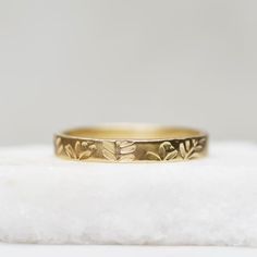 a gold ring with leaves on it sitting on top of a piece of white rock