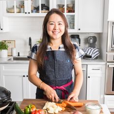 a woman in an apron cutting up vegetables