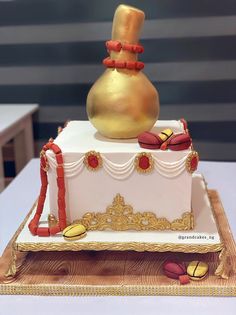 a white and gold decorated cake with a large golden vase on it's top