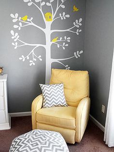 a chair and ottoman in a room with a tree painted on the wall