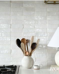 wooden spoons and spatulas in a white vase on a kitchen counter