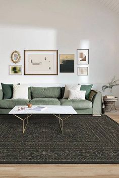 a living room with green couches and pictures on the wall above it's coffee table