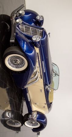 an antique blue car is parked in front of a white wall