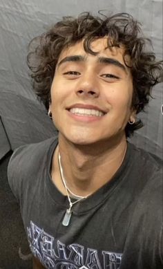 a young man with curly hair smiling at the camera