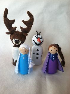 three small toy figures are standing next to each other on a white sheet with snowman and reindeer