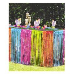 the table is decorated with fringes and candles for an outdoor party or celebration in bright colors