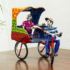 two skeletons riding on a colorfully painted tricycle