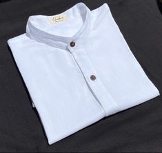 Mandarin collar shirt White  What distinguishes our shirt? There are several details that make our shirt unique. Like the rest of our collection, it is made of cotton and bamboo, two natural fibers that when put together give us a very soft texture. It is the shirt that you will not want to take off for its high comfort and freshness. Flax and bamboo have many benefits for the planet and for those who use them. Both materials are friendly to the skin, in addition to being hypoallergenic, they protect against UV rays. The buttons are made of shell. Every detail of this piece is natural, ecological and biodegradable. * Important: you can choose to order it in black, white, army green, gray / purple, brown and blue. * You can also indicate if you want it with a line or without a line and the Traditional White Linen Shirt, White Linen Shirt With Buttons, Classic White Shirt With Stand Collar, Mandarin Collar Blouse, Mandarin Collar Shirt, Blouse White, Collar Blouse, Collar Shirt, Soft Texture