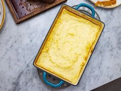 a pan filled with food sitting on top of a counter next to plates and utensils