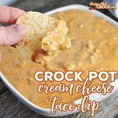 a hand holding a cracker over a bowl of cream cheese taco dip