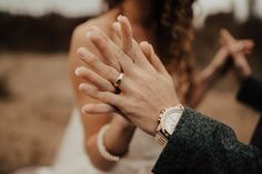 a man and woman holding hands in front of each other with their wedding rings on