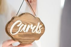 a person holding a wooden sign that says cards