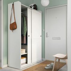 a white wardrobe with two doors and a brown bag hanging on the door