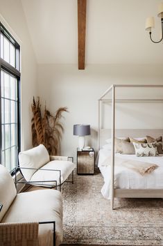 a white bed sitting in a bedroom next to a couch and chair on top of a rug