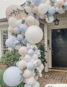 a bunch of balloons that are on the side of a house in front of a door