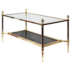 a glass and brass coffee table with two shelves on the bottom, one shelf is turned upside down