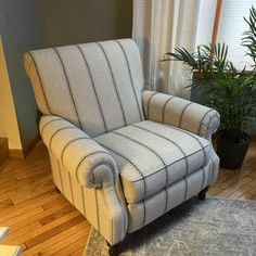 a living room with a chair, rug and potted plant in the corner on the floor