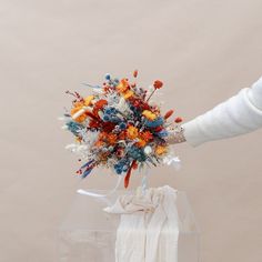 a bouquet of flowers is being held by someone's hand in a clear vase