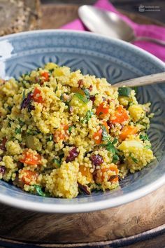 a bowl filled with rice and vegetables on top of a wooden table