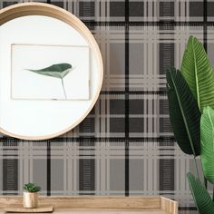 there is a mirror and some plants on the table in front of this plaid wallpaper