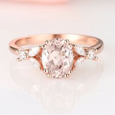 a pink diamond ring with three diamonds on the band and an oval shaped center stone