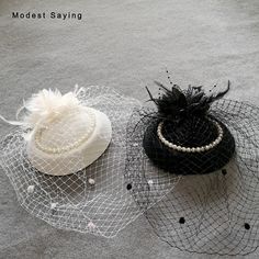 two hats with veils and pearls on them sitting on the ground next to each other