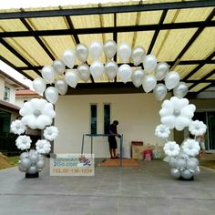 an outdoor event with white balloons on the ground and a man standing in the doorway