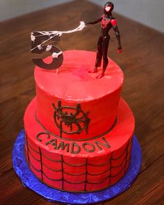 a spiderman cake on a table with the name canon spelled in red frosting