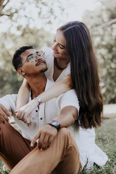 a man and woman sitting in the grass