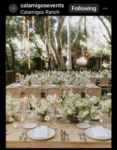 the table is set with white flowers and place settings for guests to sit down at