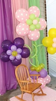 a rocking chair with balloons attached to it and flowers in the air next to them