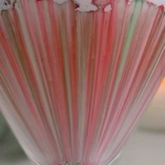 a glass vase filled with candy canes sitting on top of a white table next to a candle