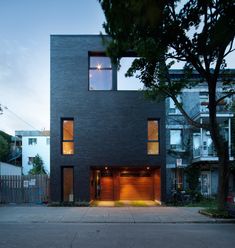 an apartment building with two garages on the front and one in the back, is lit up at night