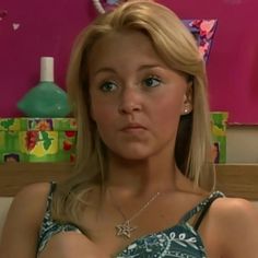 a woman sitting on top of a couch in front of a pink wall and wearing a tiara